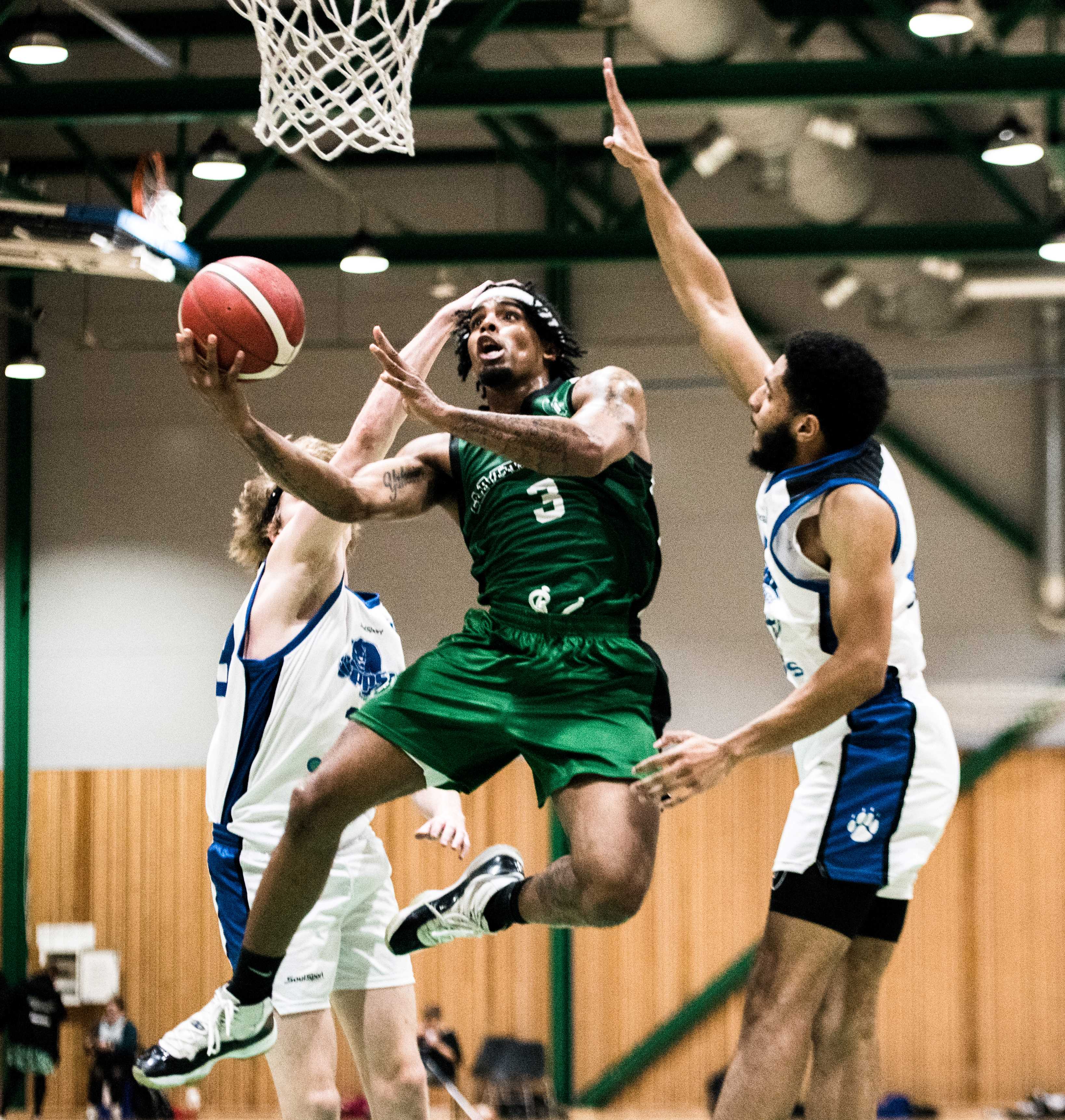 Xavier Sewell har drivet seg gjennom Oppsal-forsvaret, flyr forbi Jonathan Linnestad (til venstre) og Jacquez Henderson og legger to av sine 25 poeng for Ammerud.
FOTO: ERIK BERGLUND 