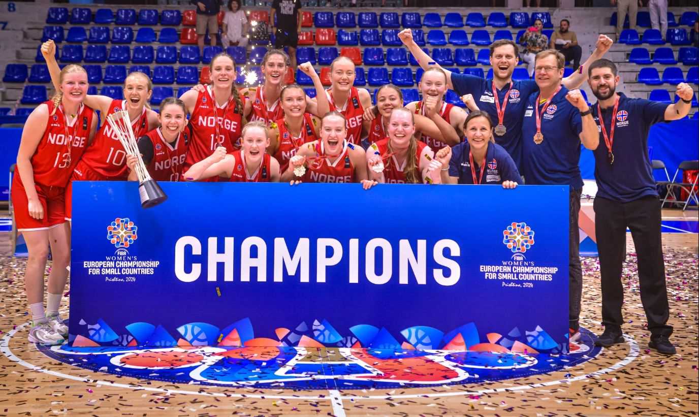 Norge er blitt kåret som mestere, har fått gullmedaljene og den store pokalen og jubler i sportspalasset i Pristina. Fra venstre ser vi Vilde Havnes, Andrea Bolstad Raa, Karoline Teigland, Tori Solberg Halvorsen, Aurora Sørbye (foran), Severine Uggen (bak), Maren Mildestvedt, Eirin Vreim Holm (foran), Synne Jacobsen (bak), Karyn Sanford, Siri Granheim, Sunniva Sørbye og coachene Jeanine Flaaten, Gunnar Nesbø, Ståle Frey og Isak Prinos.
FOTO: FIBA.COM 