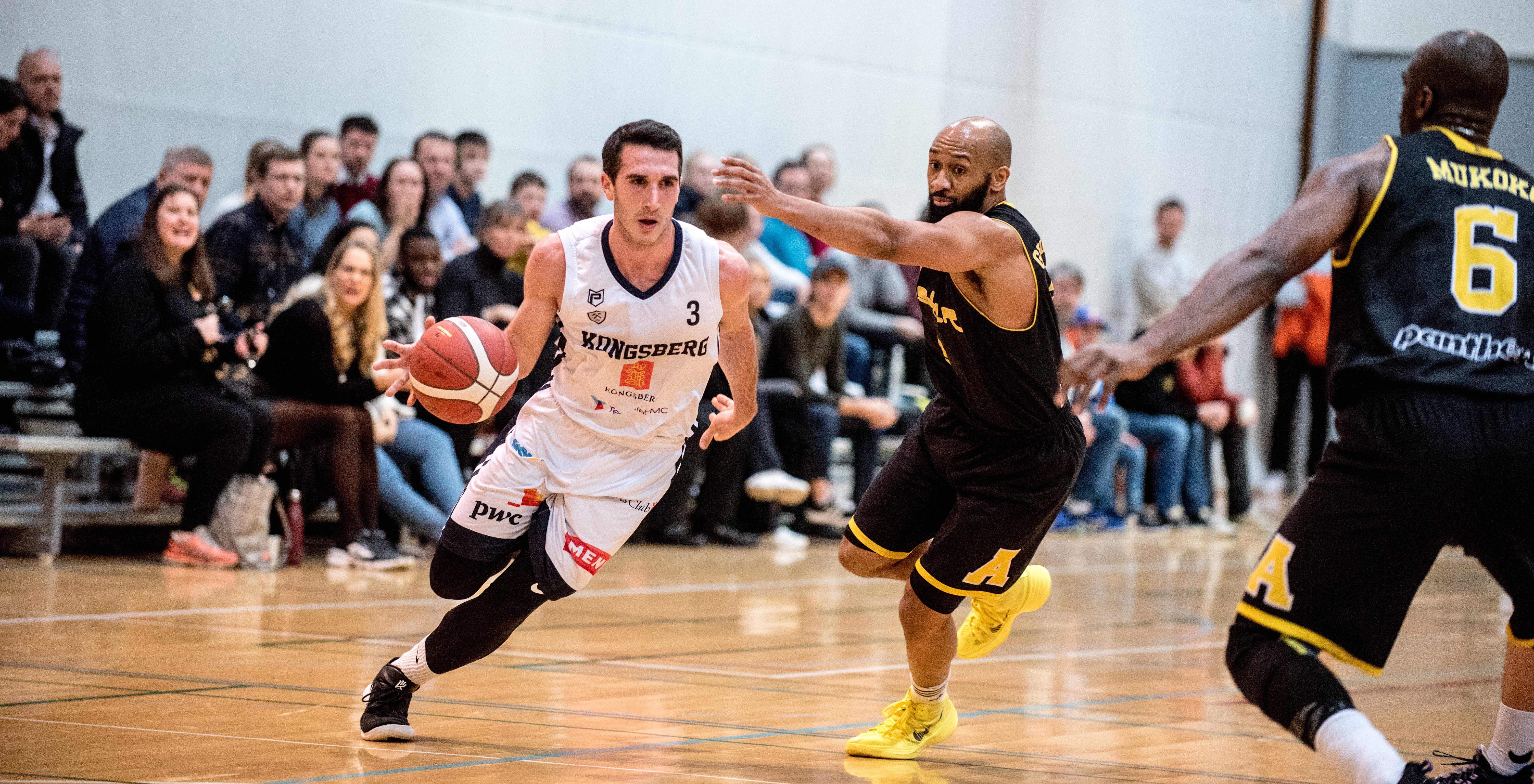 Duell mellom pointguardene og de to lags ledende spillere i mandagens BLNO-kamp: Juan Ferrales (med ballen) var toppscorer med 26 poeng, hadde 8 returer og 6 assists for Miners - og traff 14 av 14 straffer! Eric Gilchrese endte nær en triple double for Asker - med 21 poeng, 9 assists og 8 returer. Til høyre i bildet er Plaisir Nzitani Mukoko. FOTO: ERIK BERGLUND