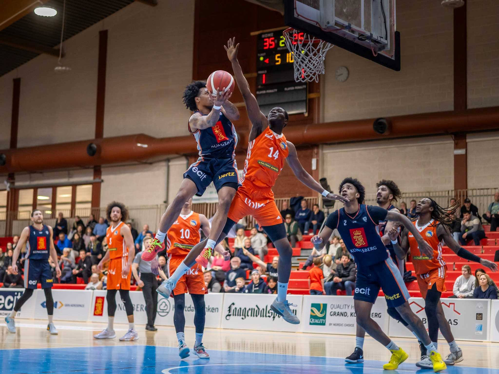 AJ Harris svever høyt, legger to poeng, blir feilet av Haji Jawara og setter bonusstraffen til 38-26 for Kongsberg Miners midtveis i andre periode. I bakgrunnen til venstre ser vi Marin Mornar, Eric Fongué og Nikolas Skouen, til høyre Jordan Roberts, Aly Hudgins og Terrell Brown.
FOTO: ESPEN SANDENGEN 