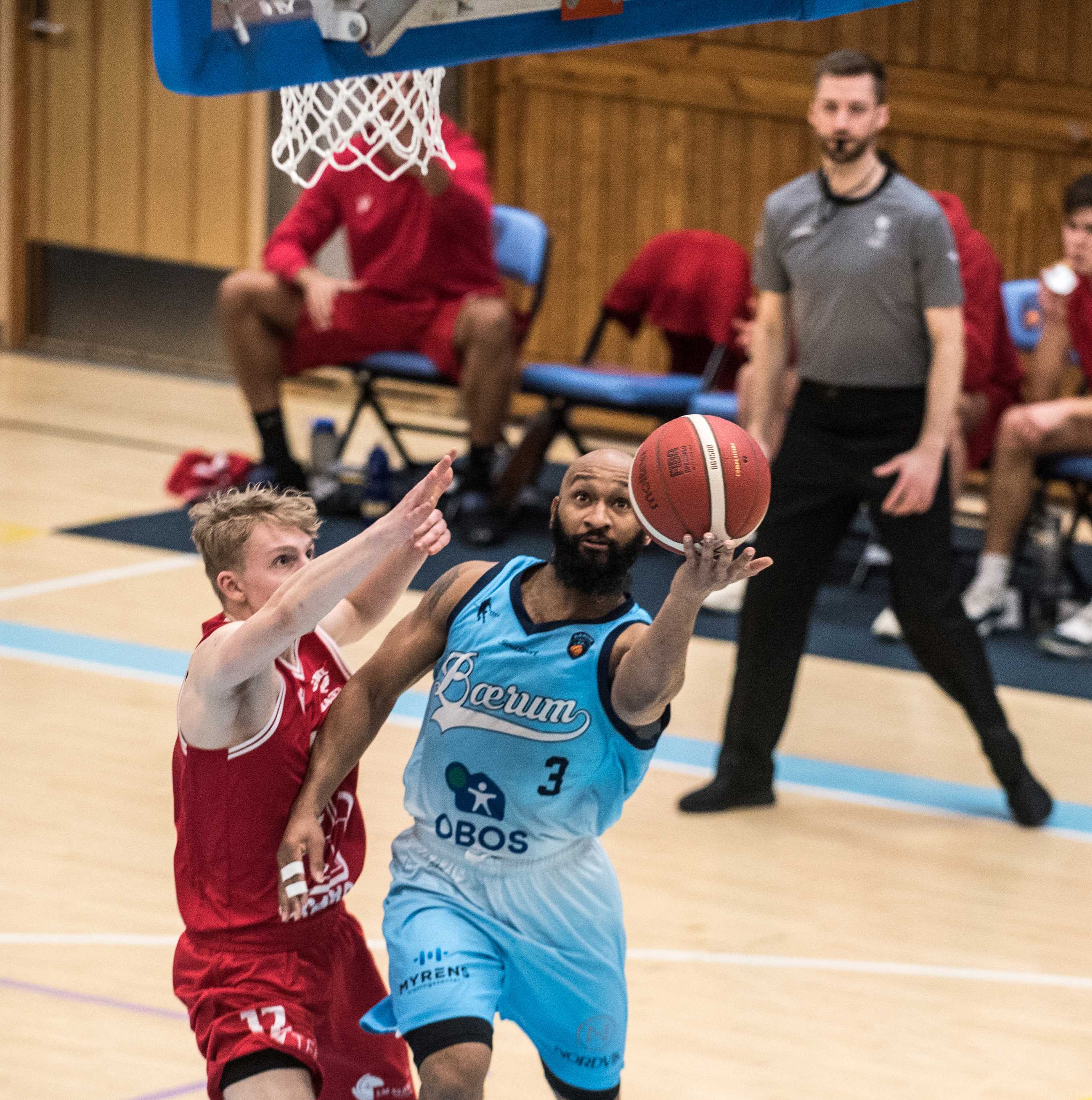 Eric Gilchrese hadde 14 poeng og 8 assists for Bærum. Her er den amerikanske pointguarden i en layup mot Gimles toppscorer i kampen, 19-årige Kristoffer Gjerde Sætren. Bak ser vi dommer Torkild Rødsand.
FOTO: ERIK BERGLUND 