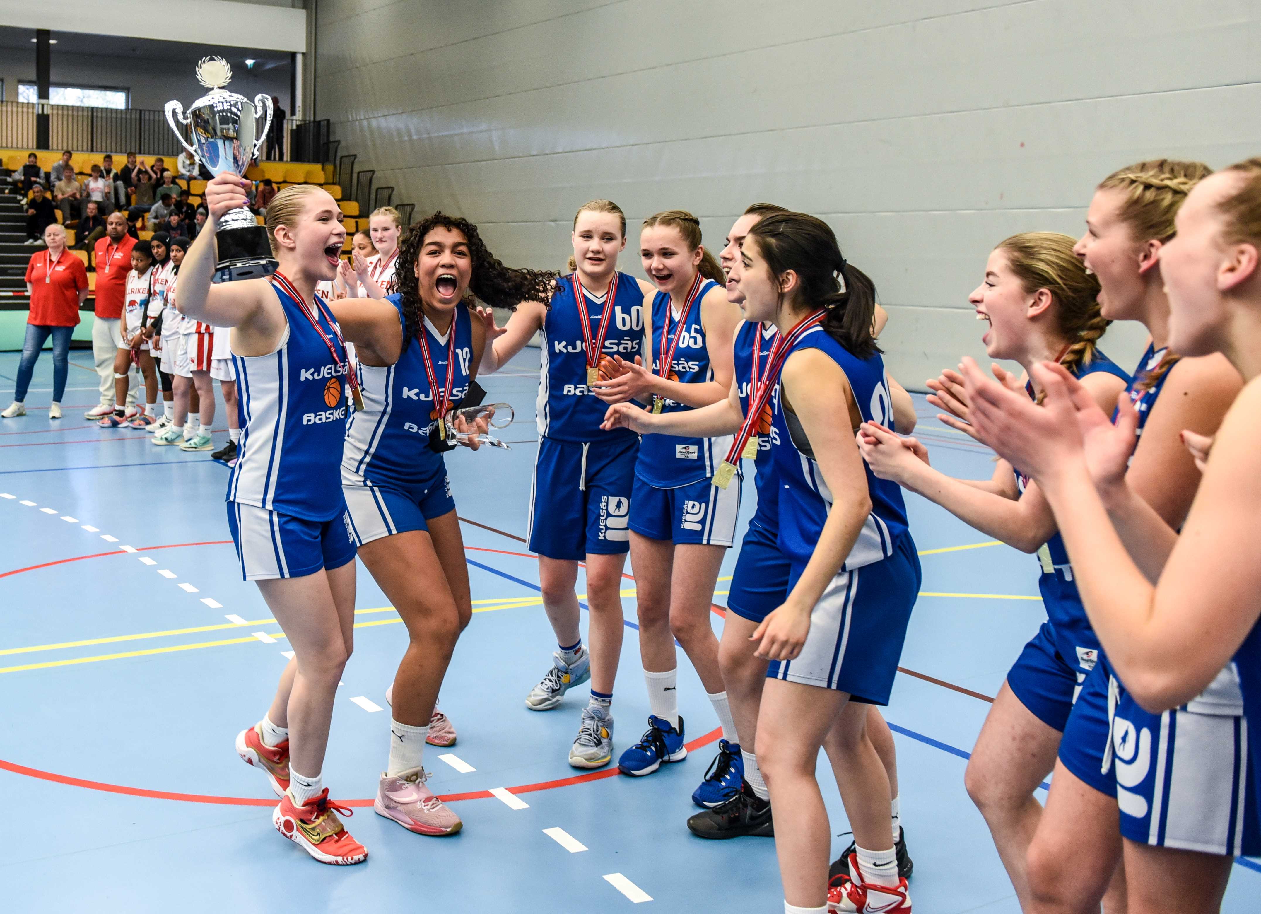 Her jubler lagkaptein Rakel Sif Omarsdottir, MVP Andrea Fergem Faal og de andre Kjelsås-jentene etter 61-54 over Ulriken Eagles i U16-NM på Hønefoss 30. april. Da var åtte lag direktekvalifisert for sluttspillet, nå er 20 lag påmeldt og må kjempe om 12 plasser til neste års NM, som arrangeres av Ammerud 26.- 28. april.
FOTO: ERIK BERGLUND 