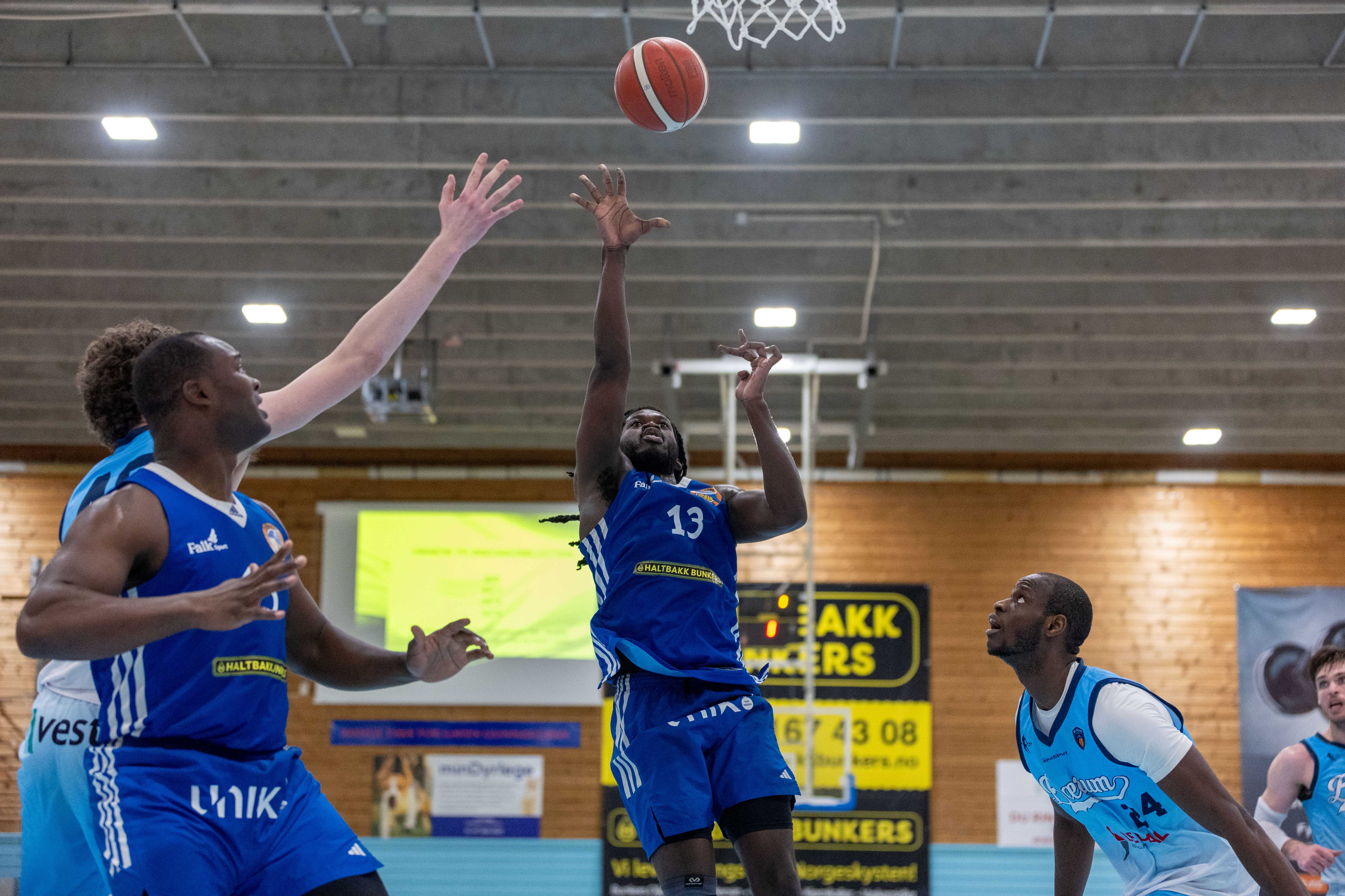 Isaac Likekele var overalt i den første finalen og endte med en råsterk triple-double: 17 poeng, 17 returer og 12 assists. Her legger han et skudd over Aksel Borg (delvis skjult), mens Ousseynou Mbow (til høyre) også er sjanseløs på å stoppe amerikaneren. Til venstre i bildet er superveteran Peter Bullock (41) klar for retur, mens vi ser Sjur Dyb Berg i høyre bildekant.
FOTO: BRAGE TITLESTAD 