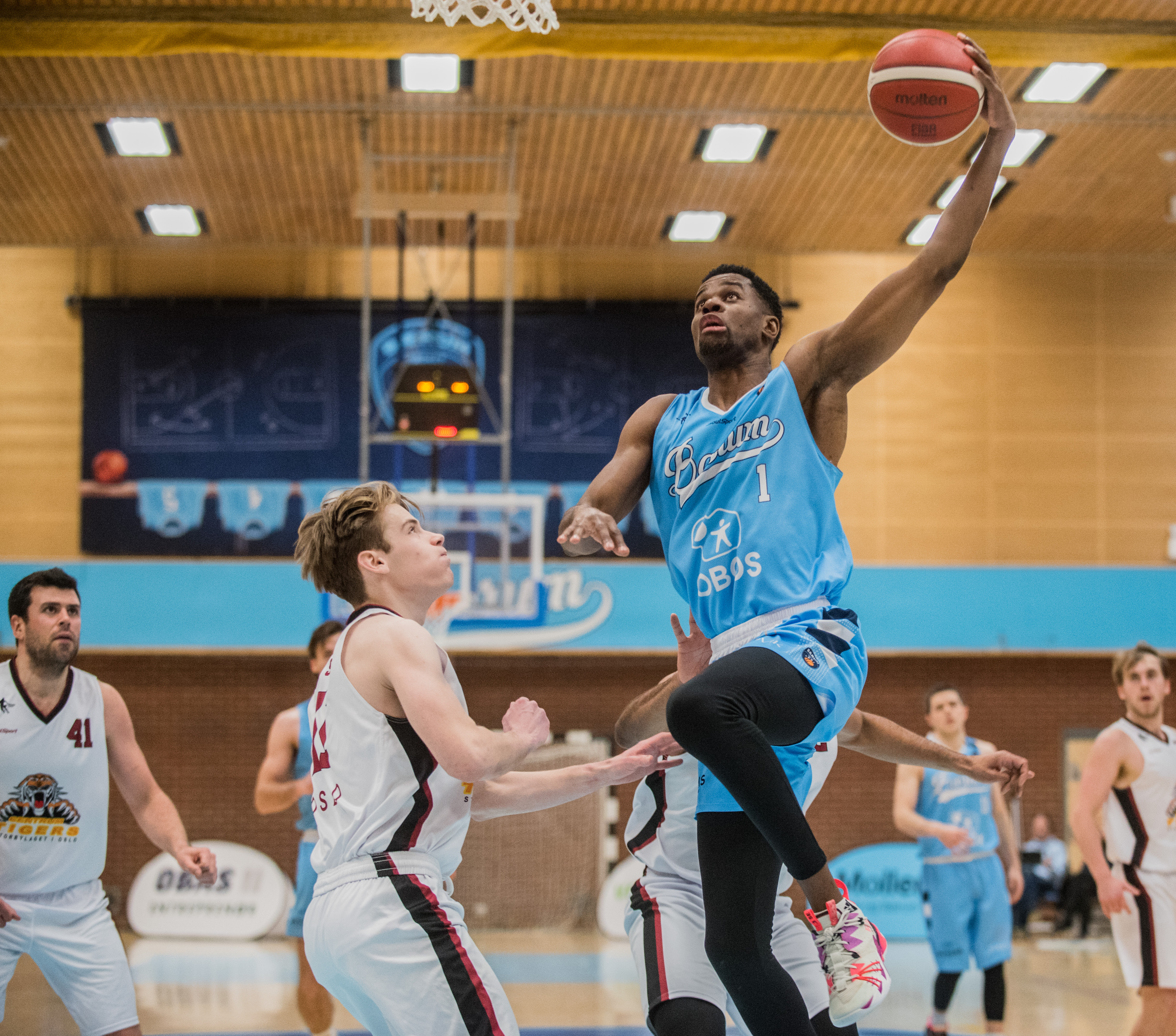 Yannick Anzuluni var i showhumør for Bærum og endte på 12 poeng, 7 assists og 3 steals etter å ha tilbrakt mye tid på benken de siste to periodene på grunn av foultrøbbel. Her legger 33-åringen en layup over Sigurd Sandlie. Til venstre i bildet er Tarjei Bryn.
FOTO: ERIK BERGLUND  