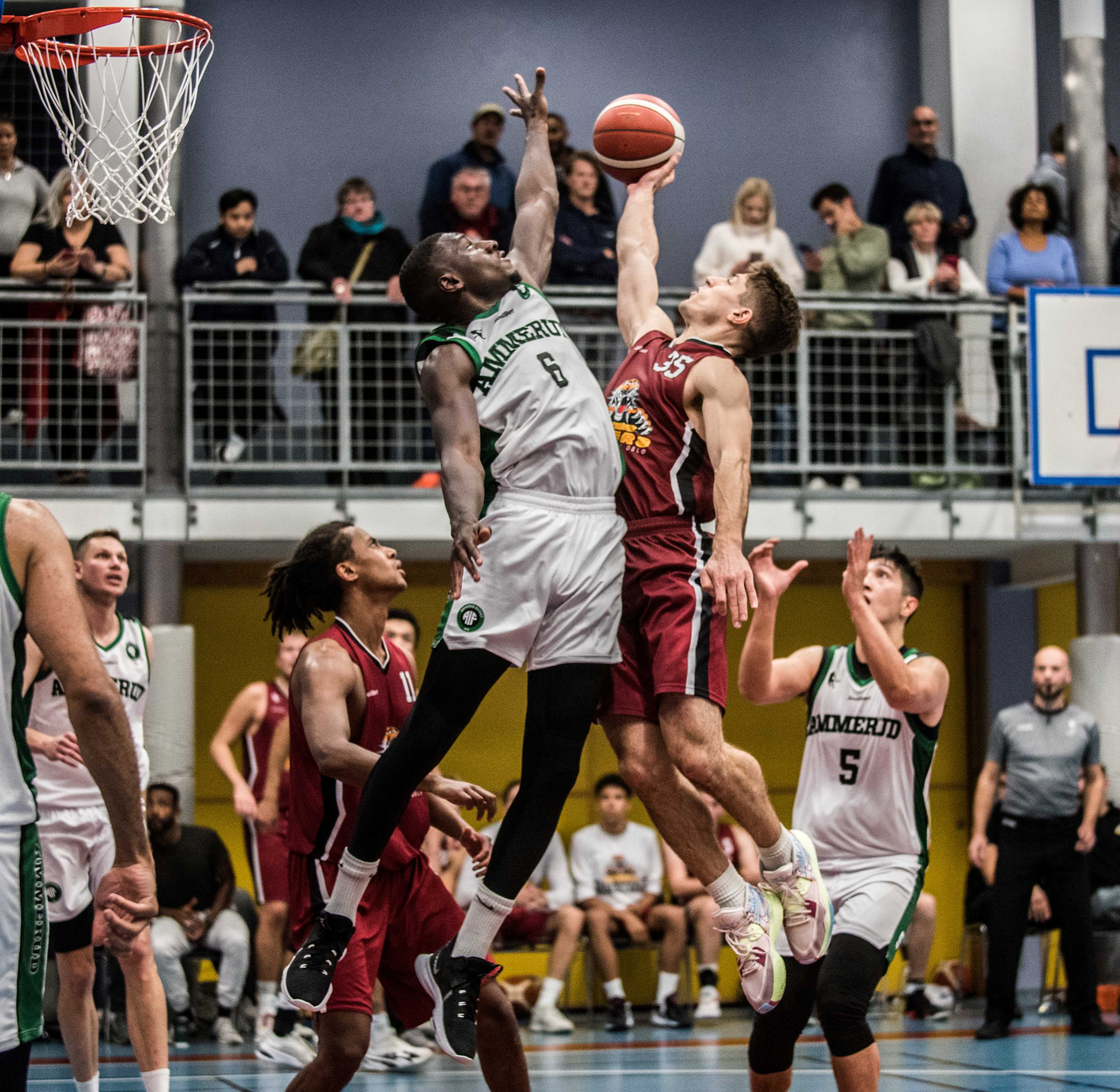 Kveldens høydepunkt i Vulkanhallen: 1,5 sekund før slutt i 2. periode tar Pat Dickert innspillet fra Ulrik Stranger-Johannessen i lufta og legger inn en buzzerscoring til 53-32 over Mustafa Dibba. Til høyre i bildet er Kevin Austria, til venstre ser vi Oliver Bojang Visnes og Ammeruds Sebastian-Ionut Slabu.
FOTO: ERIK BERGLUND 