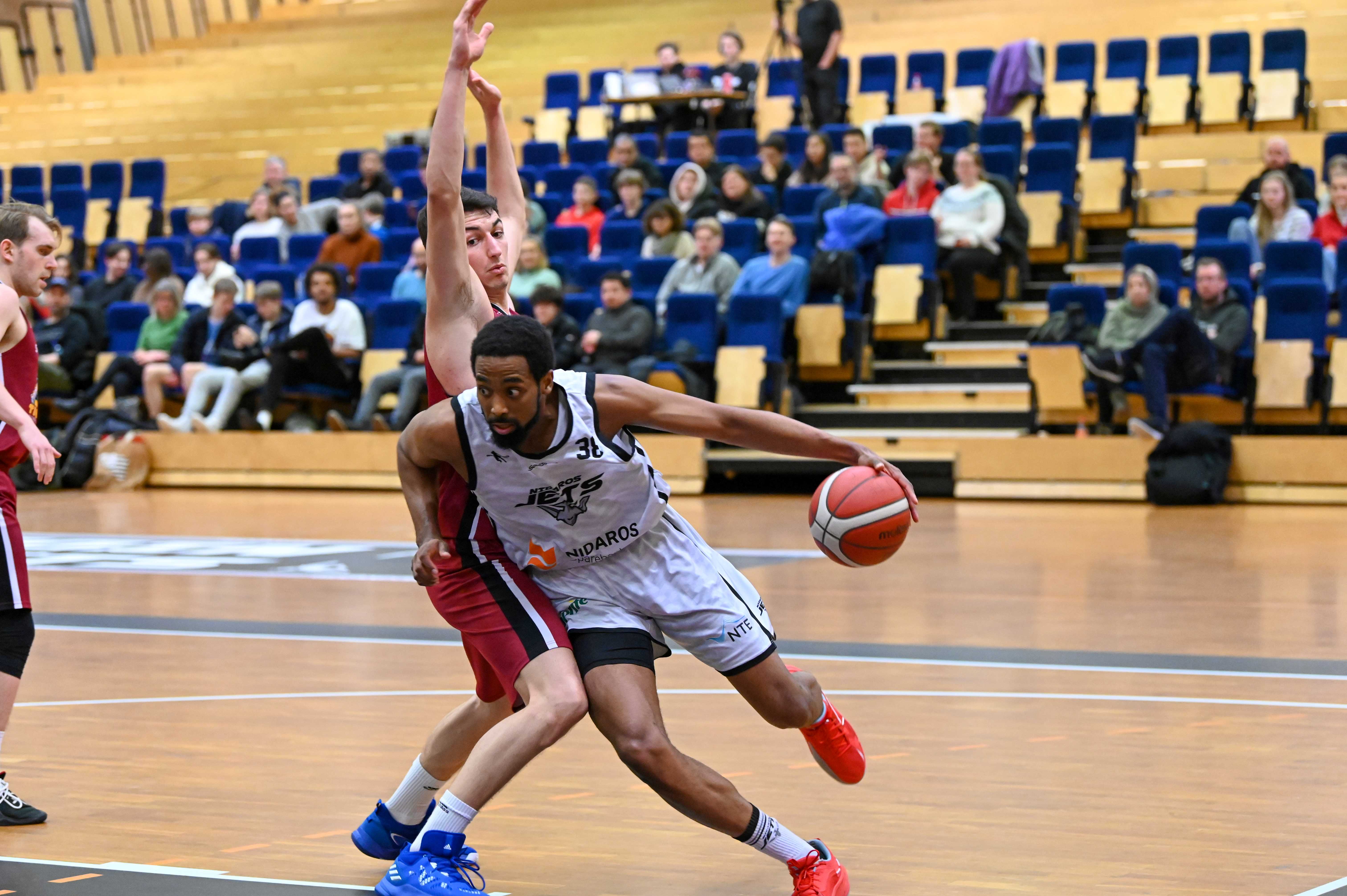 Chris Carter var vrien å stoppe for Centrum Tigers i andre del av kampen: Etter 4 poeng ved pause, ble amerikaneren toppscorer med 25. Her runder Nidaros-forwarden gjestenes mestscorende og beste spiller, Giorgos Kotrotsios, som hadde 15 poeng og 11 returer. I venstre bildekant ser vi Simon Midtvedt.
FOTO: LARS RUNE SKAUG 