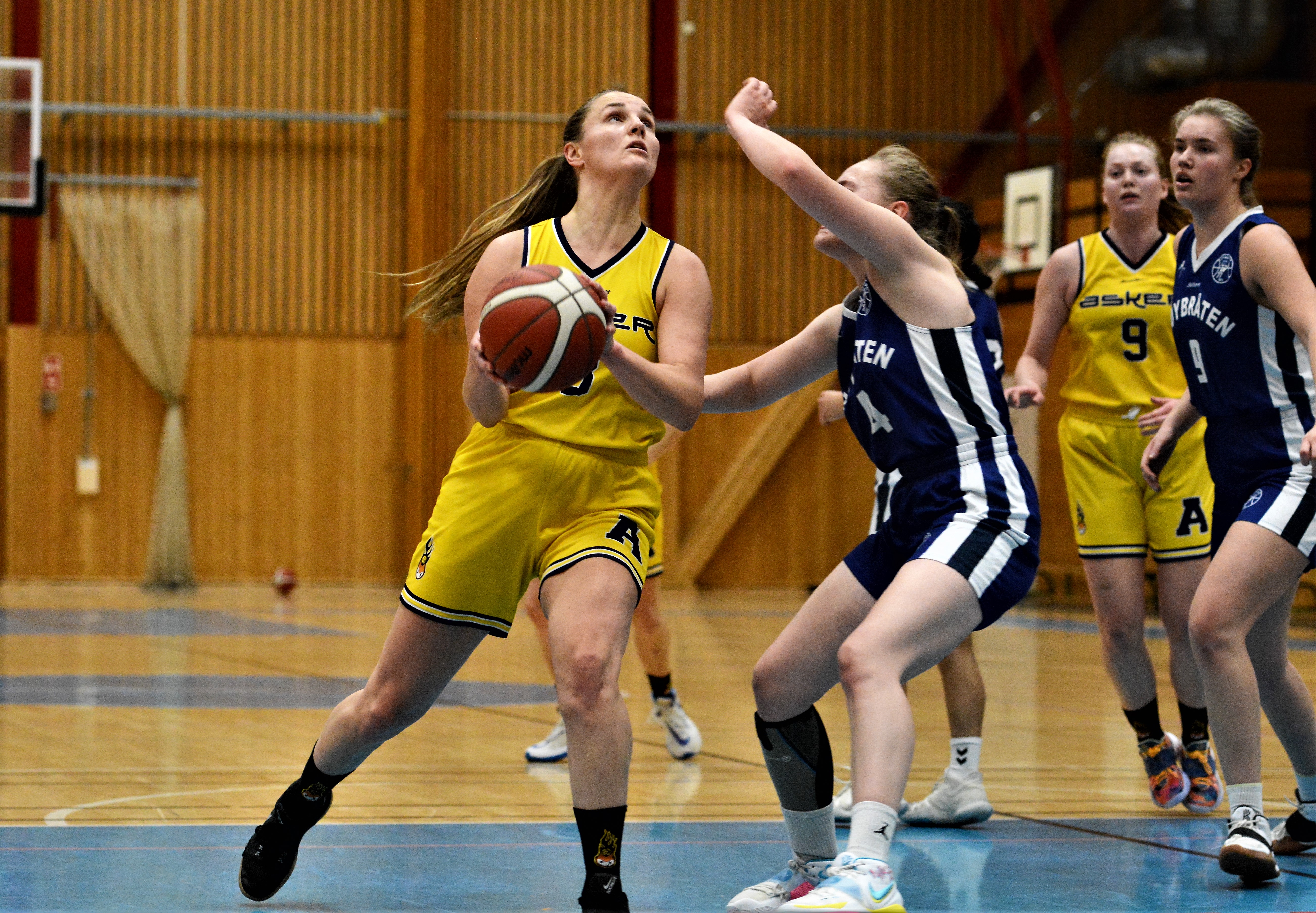 Ingrid Selvik var banens dominerende spiller da Asker Aliens slo Høybråten 99-41. Hjemmelagets kaptein hadde flest poeng (19), returer (14), steals (7) og assists (4) i kampen. Her skyter hun forbi Jofrid Jansen Gjersvik. Til høyre i bildet er Askers Siri Granheim og Høybråtens Frida Liholm Strøm.
FOTO: MARIANNE MAJA STENERUD 