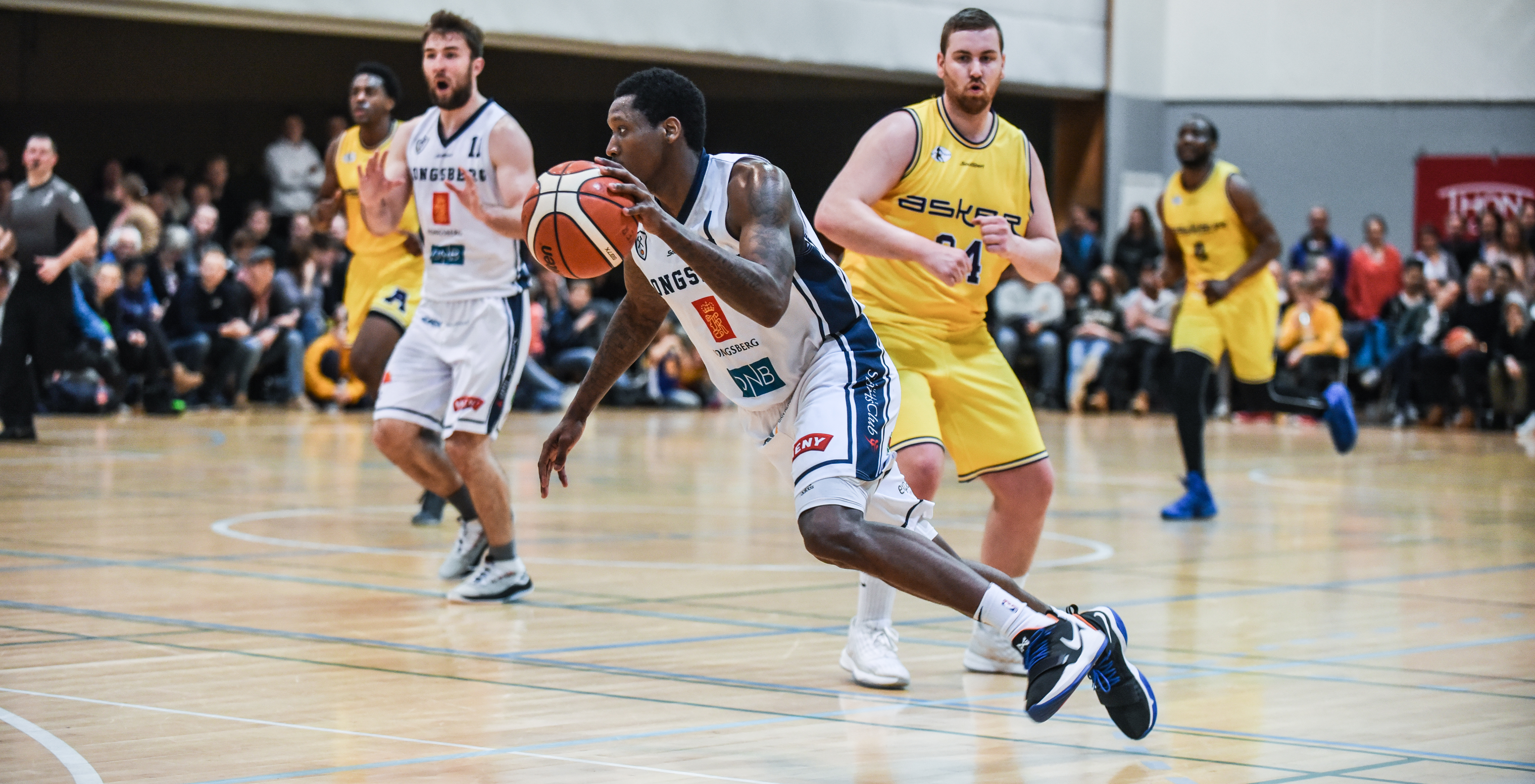 Fred Thomas var toppscorer i første og tredje NM-finale mot Asker Aliens i 2018, begge ganger i Leikvollhallen. Nå er 27-åringen klar for sin andre periode i Kongsberg Miners, etter to sesonger med Bristol Flyers i den britiske toppserien. På bildet driver Thomas forbi Anders Stien, og bak ser vi fra venstre Joshua Hart, Brian Voelkel og Djo Loo Yele.
FOTO: ERIK BERGLUND 