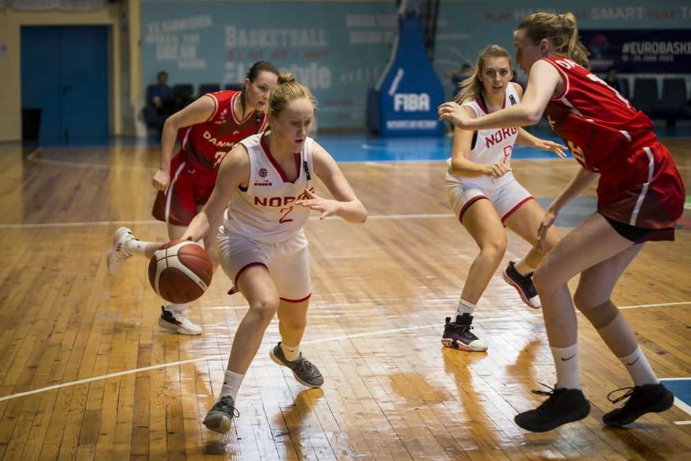 Aurora Sørbye finter bort 1,88 m høye Karen Dalsgaard og driver mot danskenes kurv. Bak til høyre ser vi Sunniva Vik Pettersen.
FOTO: FIBA.COM 