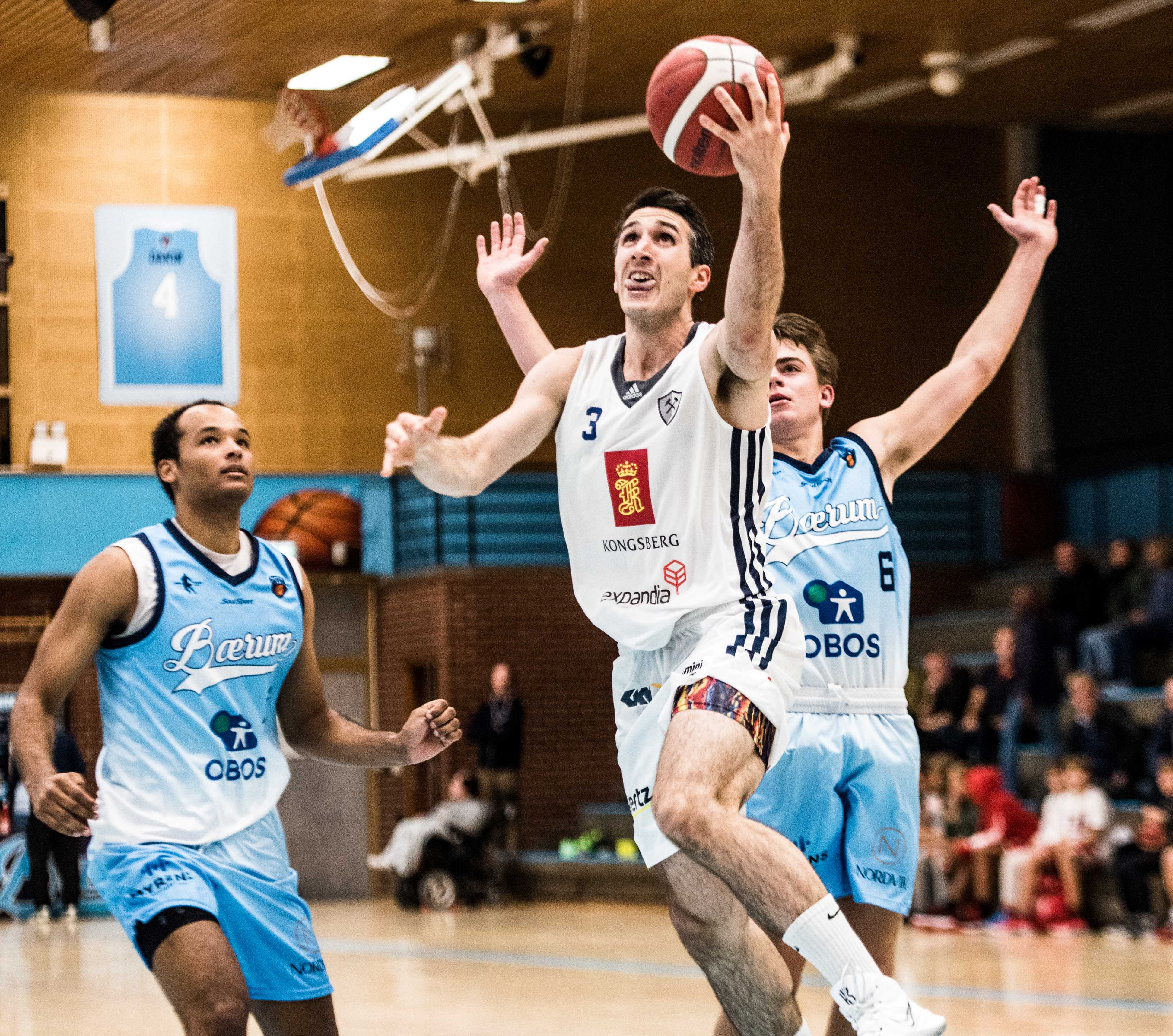 Juan Ferrales har kommet seg forbi Oscar Hellebust og legger to av sine 19 poeng. Bærums BLNO-debutant Steffon Mitchell til venstre.

FOTO: ERIK BERGLUND 
