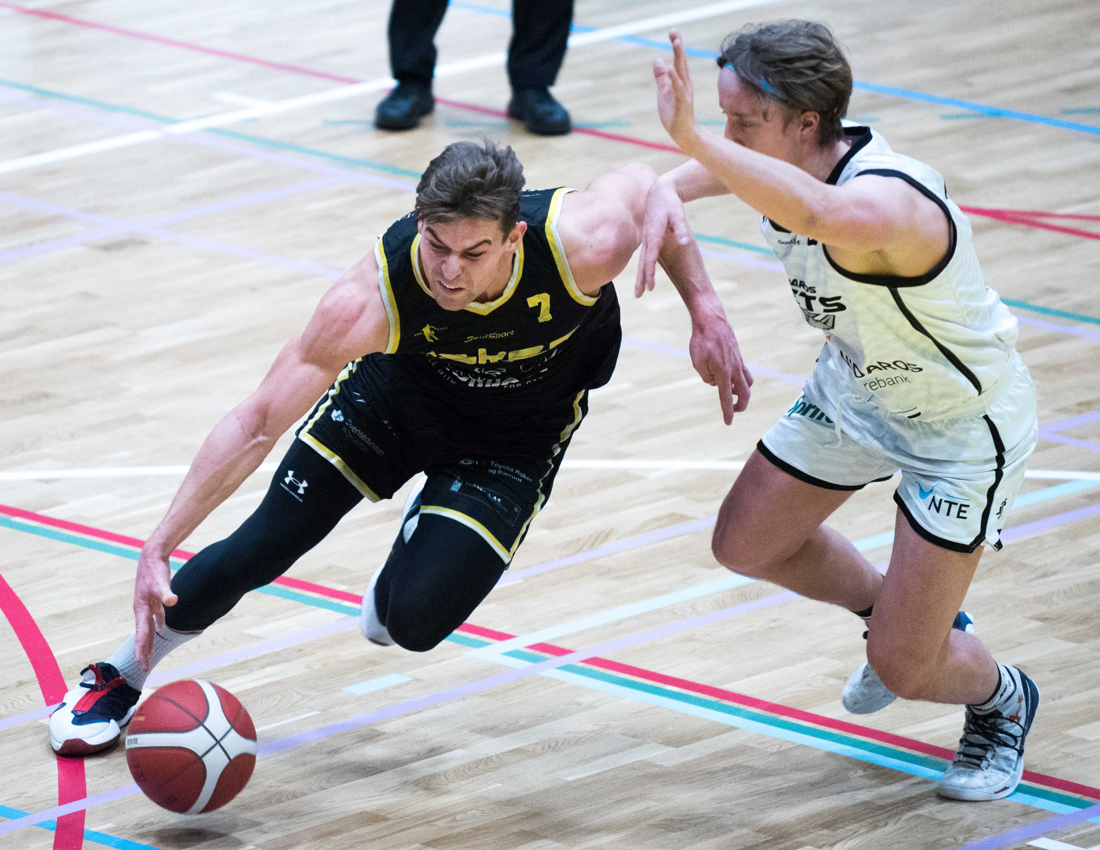 Med 21 poeng og 12 returer var Haakon Hellebust sentral da Asker Aliens slo Nidaros Jets 85-74 i sin første hjemmekamp i Nye Leikvollhallen. På bildet er Asker-forwarden i en drive mot Christian Tøfte.
FOTO: ERIK BERGLUND  