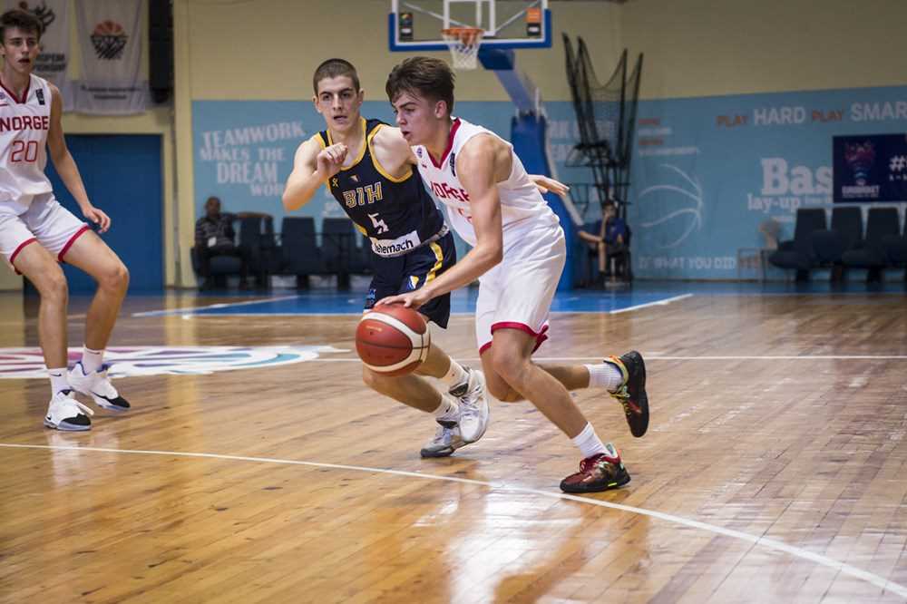 Oscar Hellebust er en garantist for scoringer i Norges U16-landslag, men mot Bosnia-Hercegovina måtte han nøye seg med 10 poeng etter en kamp der både han og laget slet med å finne veien til kurven og treffe skuddene. Her driver lagkapteinen mot bosniernes nummer 5, Pavle Egic. Ludvik Bergseng til venstre i bildet.
FOTO: FIBA.COM 