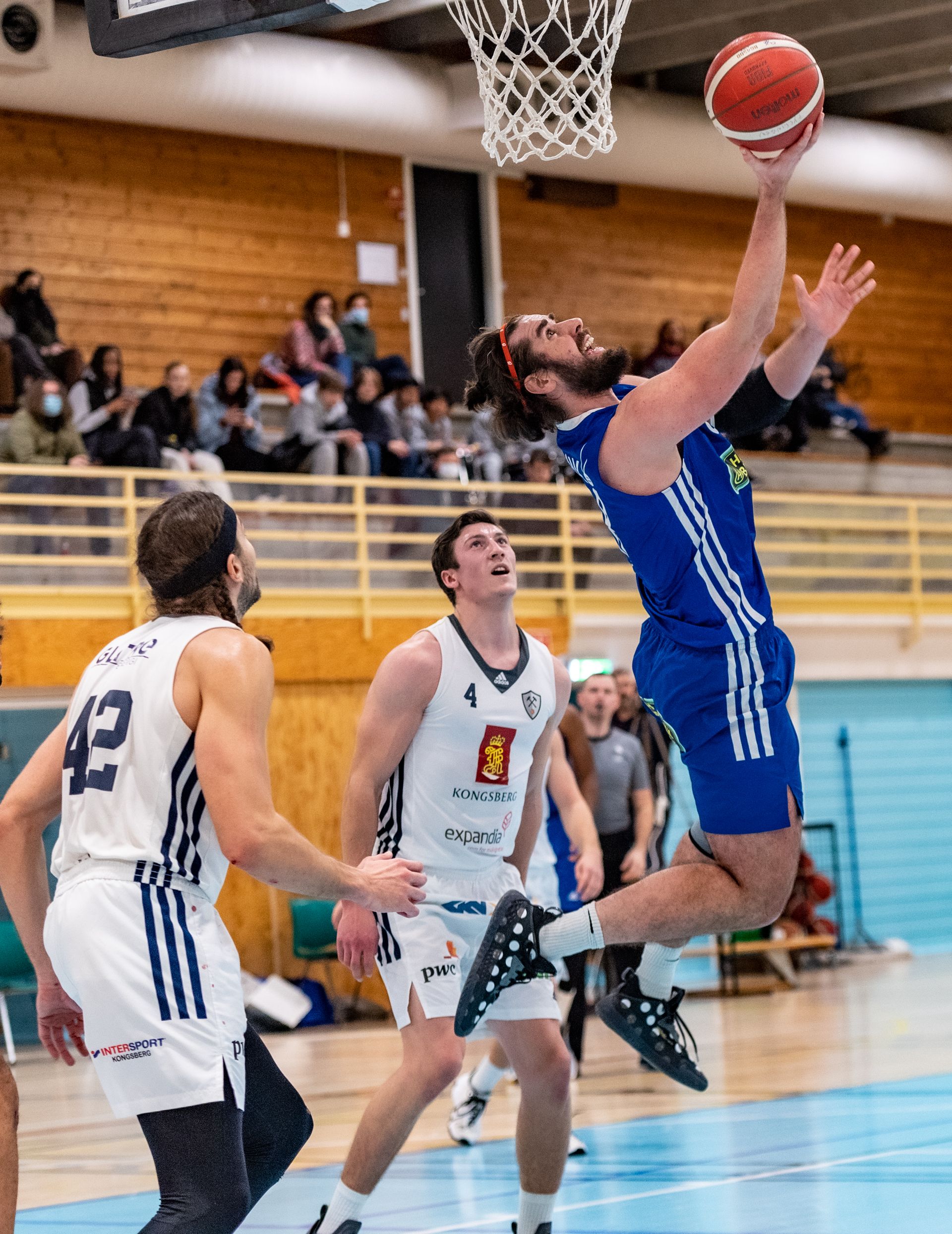 Magne Fivelstad ble nok en gang matchvinner for Fyllingen med en scoring i sluttsekundene, denne gang med 95-94 over Kongsberg Miners. Her setter hjemmelagets forward to av sine 22 poeng i kampen med en reverse layup foran øynene på Marin Mornar (til venstre) og Matias Save.
FOTO: ASTRID HAGLAND GJERDE 