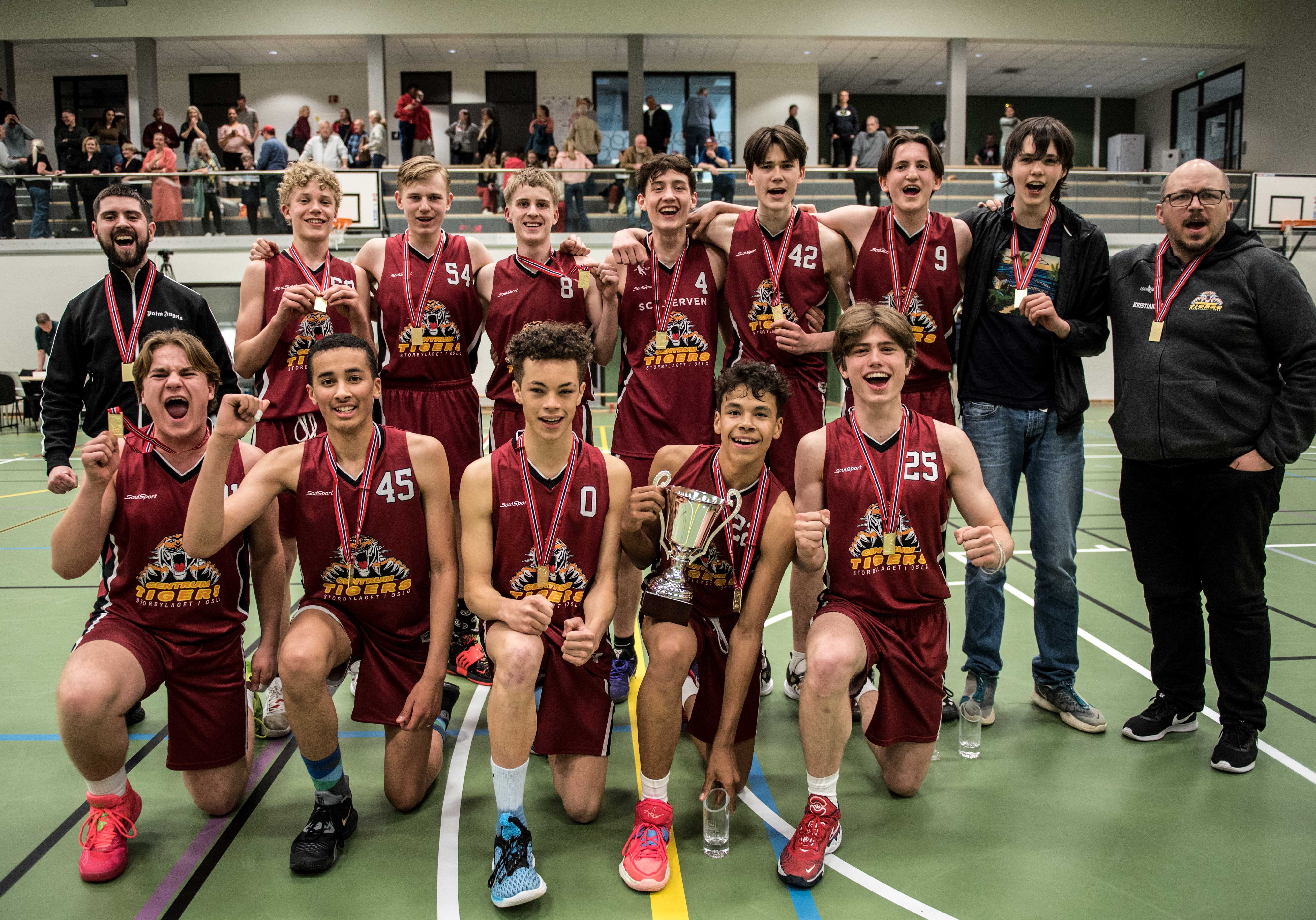 Centrum Tigers' spillere og trenere jubler med gullmedaljer etter 70-66 over Sandvika i finalen i U16-NM. Bak fra venstre Isak Prinos, Johannes Wangensteen, Gustav Goody-Eide, Storm Hospes Karlsen, Jonathan Kleven-Fredriksen, Luka Zivkovic-Tønder, Dante Olsen, Jonathan Kristoffersen og Inge-Aleksander Kristiansen. Foran fra venstre Mads Grindalen Blenne, Jeremias Isak Joseph, Silver Norment-Åsdam, Elias Demoniere og Sebastian Castellaro Hommersand.
FOTO: ERIK BERGLUND 