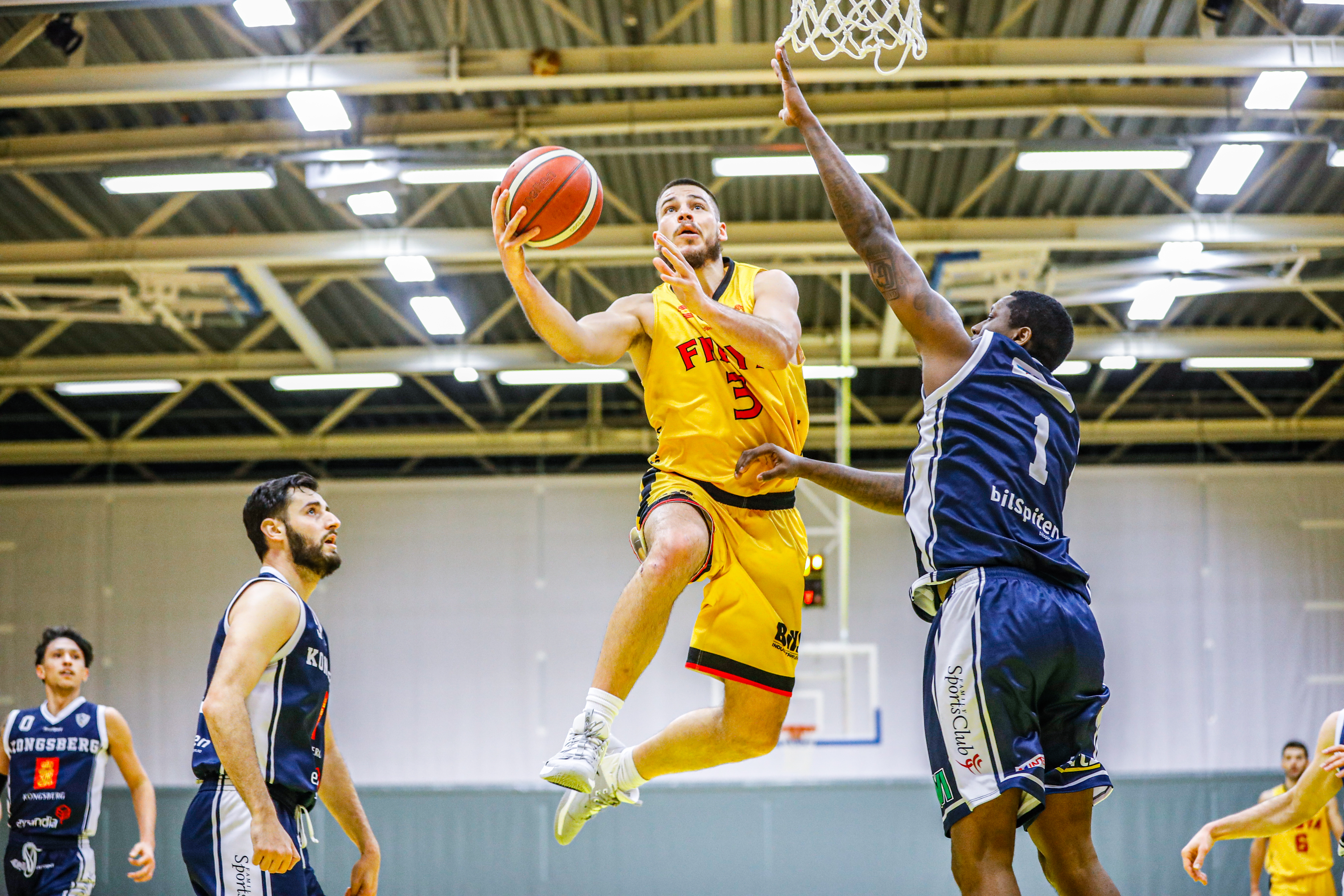 Devin Gilligan var sentral da Frøya vant 12 av sine 16 kamper i seriespillet i BLNO, og endte som ligaens nest-toppscorer og beste rebounder med 22,9 poeng og 13,4 returer i gjennomsnitt per kamp. Her er 27-åringen fra New Hampshire i en layup mot Kongsberg Miners og Fred Thomas i januar, i kampen Frøya vant 105-95. Til venstre i bildet er Ognjen Nisavic og bak til venstre Valen Tejada.
FOTO: NICHOLAS NORENG
